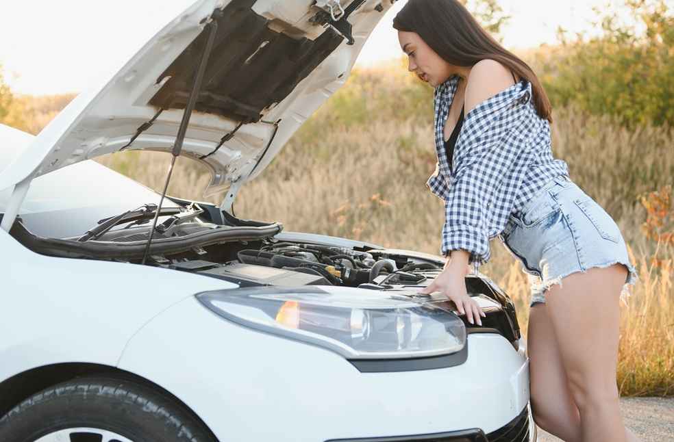 Woman checking the engine of a broken-down car - Automakers Recalls Surge-Buyers Weigh Recall Score