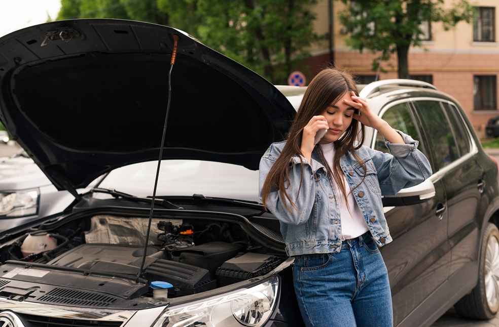 Young woman calling for help after a car breakdown - Automakers Recalls Surge-Buyers Weigh Recall Score